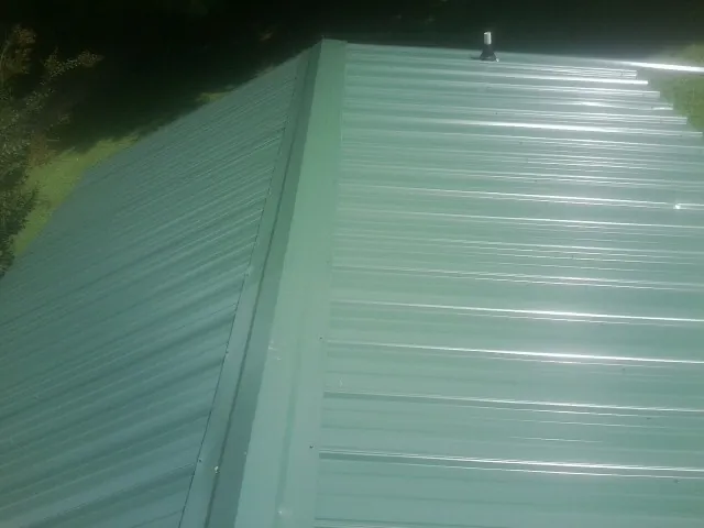 New green metal panels meeting at the ridge of a roof — Flat Roof Repair work by our crew in Green Lake
