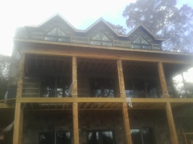 Dormers and porch framing on a large log home under construction — Roof Coating work by our crew in Green Lake