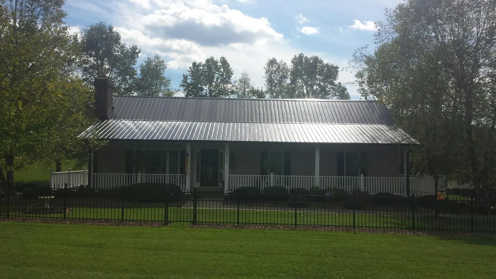 Gray metal roof on a brick ranch with a full width front porch — Gutter Guard Installation work by our crew in Green Lake