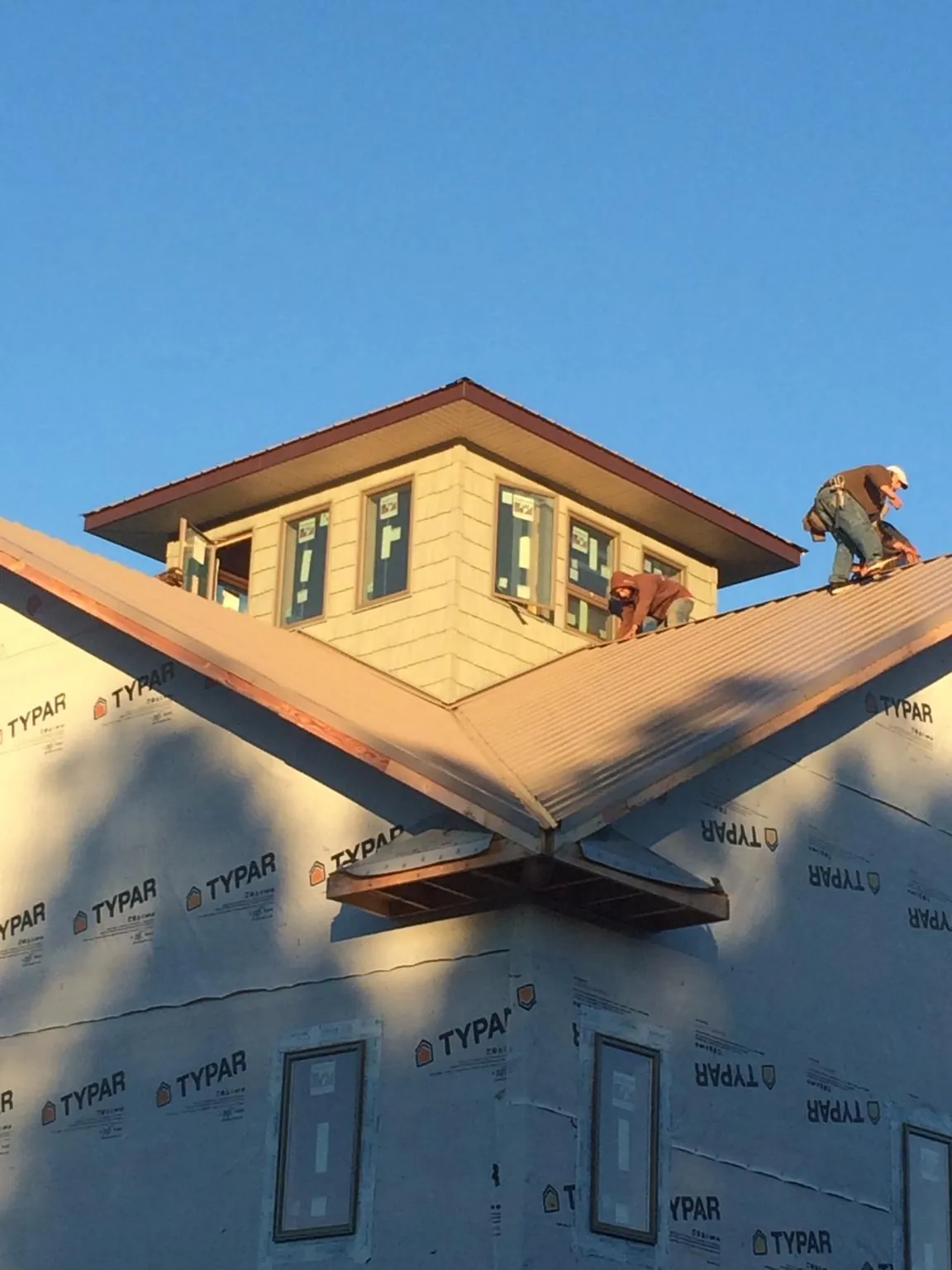 Roofers working around a rooftop cupola on a new metal roof at sunset — Roof Waterproofing in Green Lake by Roofing Brothers
